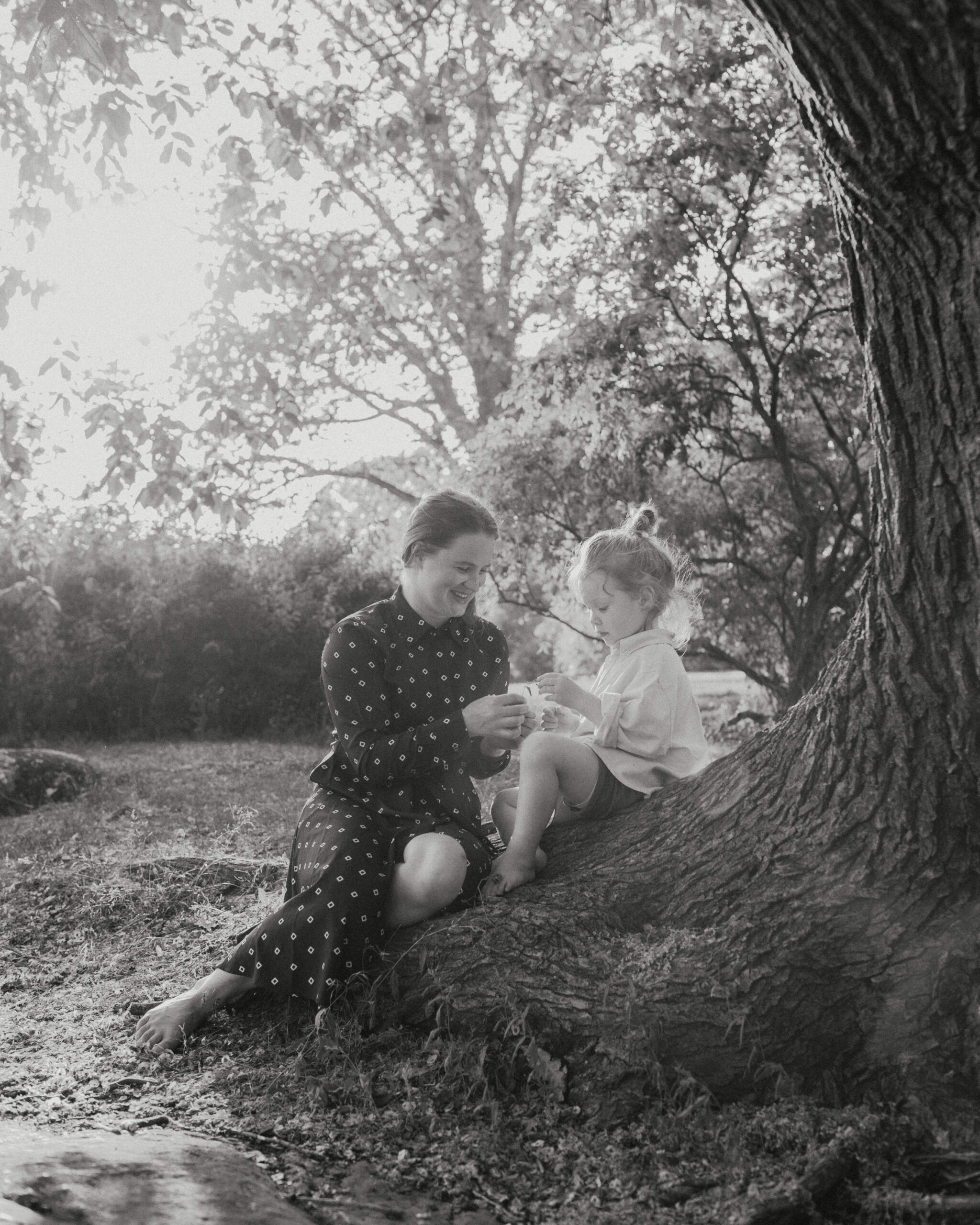 Mother and her son sitting by a big tree on summer evening in Tähtitorninvuori in Helsinki